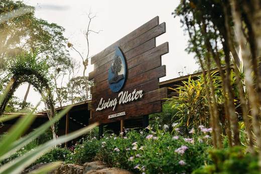 Letrero de madera de Living Water Retreat Center entre flores y plantas