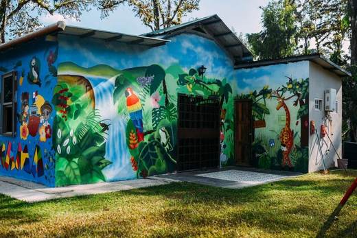 Edificio pintado con un mural de selva, con una cascada, aves y una jirafa