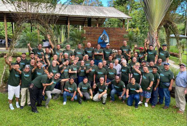 Grupo grande con camisetas verdes frente a un edificio del centro